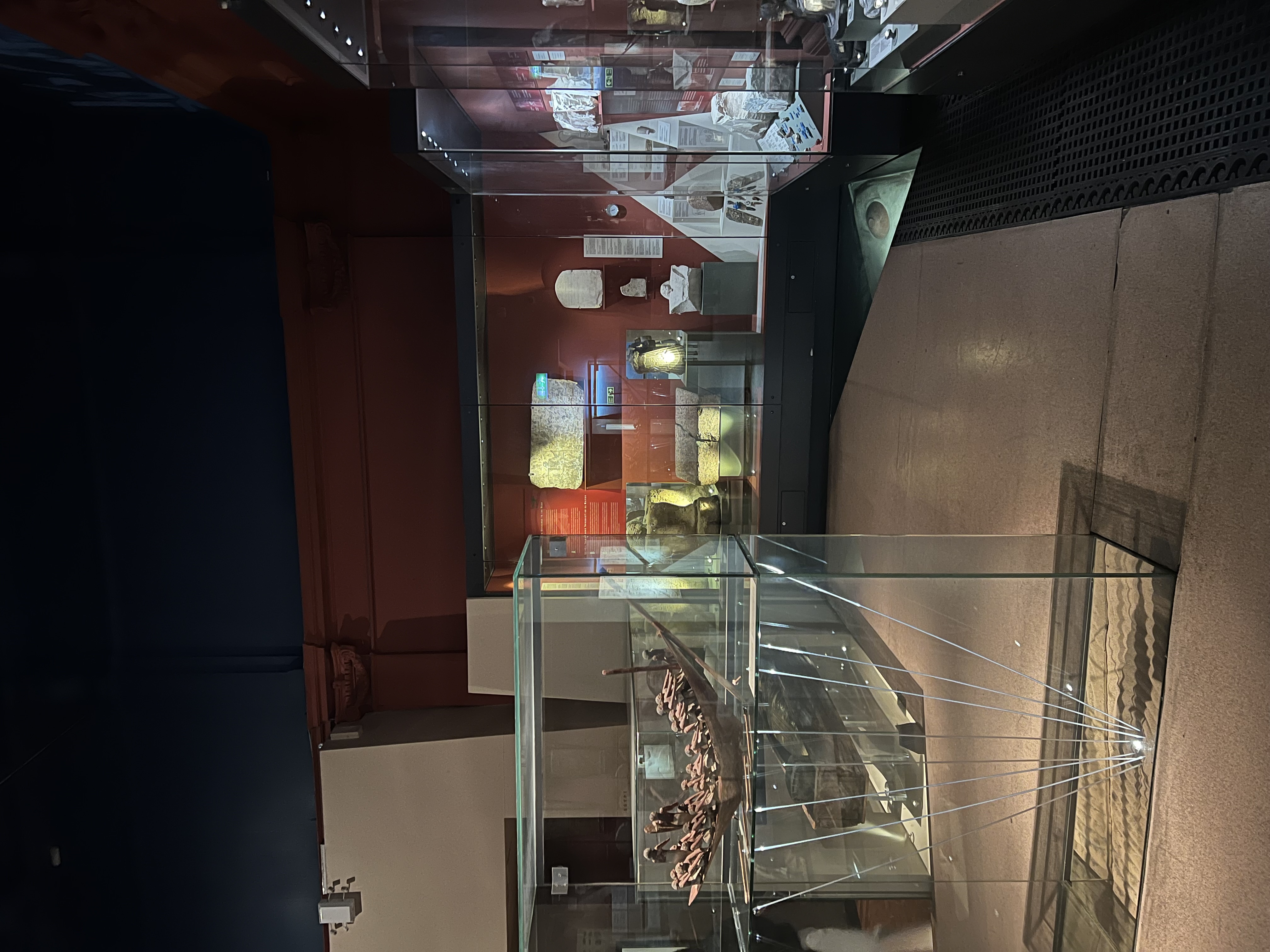 Fully glass display cases in an exhibit, there is woodwork and carved stone